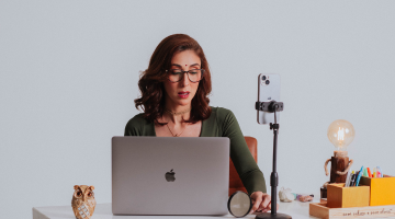 Sachi Devi Dasi à mesa de um escritório atendendo leitura de mao de quiromancia online a frente de um macbook e um Iphone